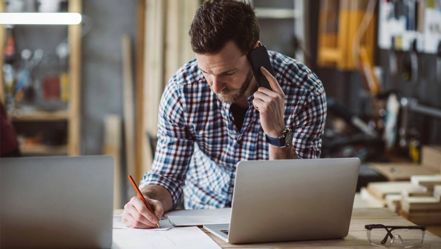 A home inspector taking a phone call while using his laptop