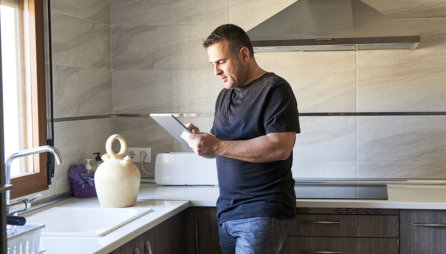 a Texas home inspector completes an inspection report using his tablet while inspecting the modern kitchen of a home