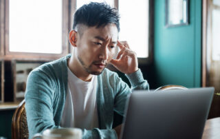 a home inspector, appearing disappointed, stares at a laptop screen