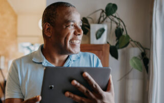 an older, retiree age man smiling and looking at a tablet - presumably researching home inspections