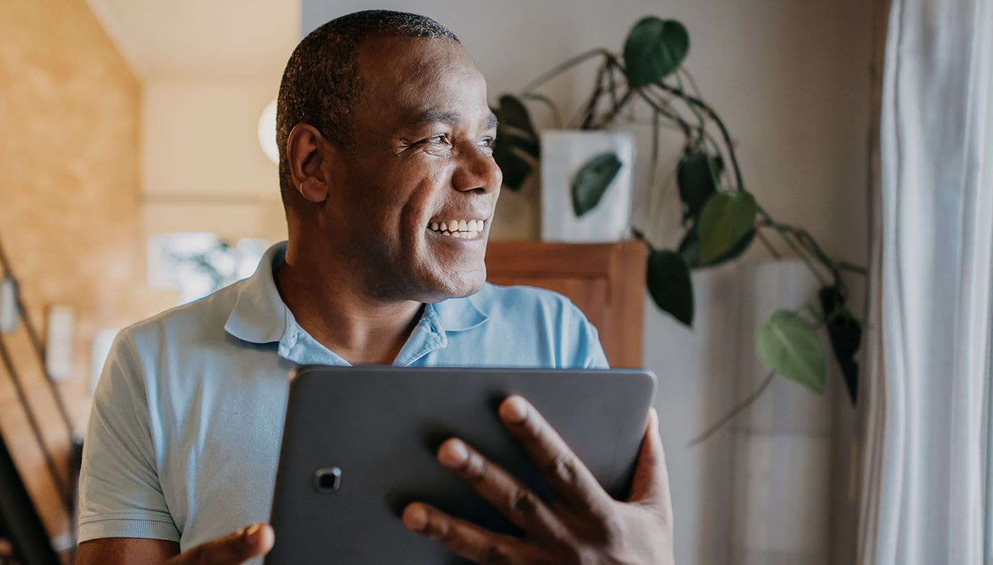 an older, retiree age man smiling and looking at a tablet - presumably researching home inspections