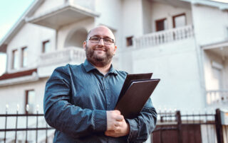 Image of home inspector standing outside of a house, with folder and clipboard in hand, presumably looking to learn about home inspection contingencies