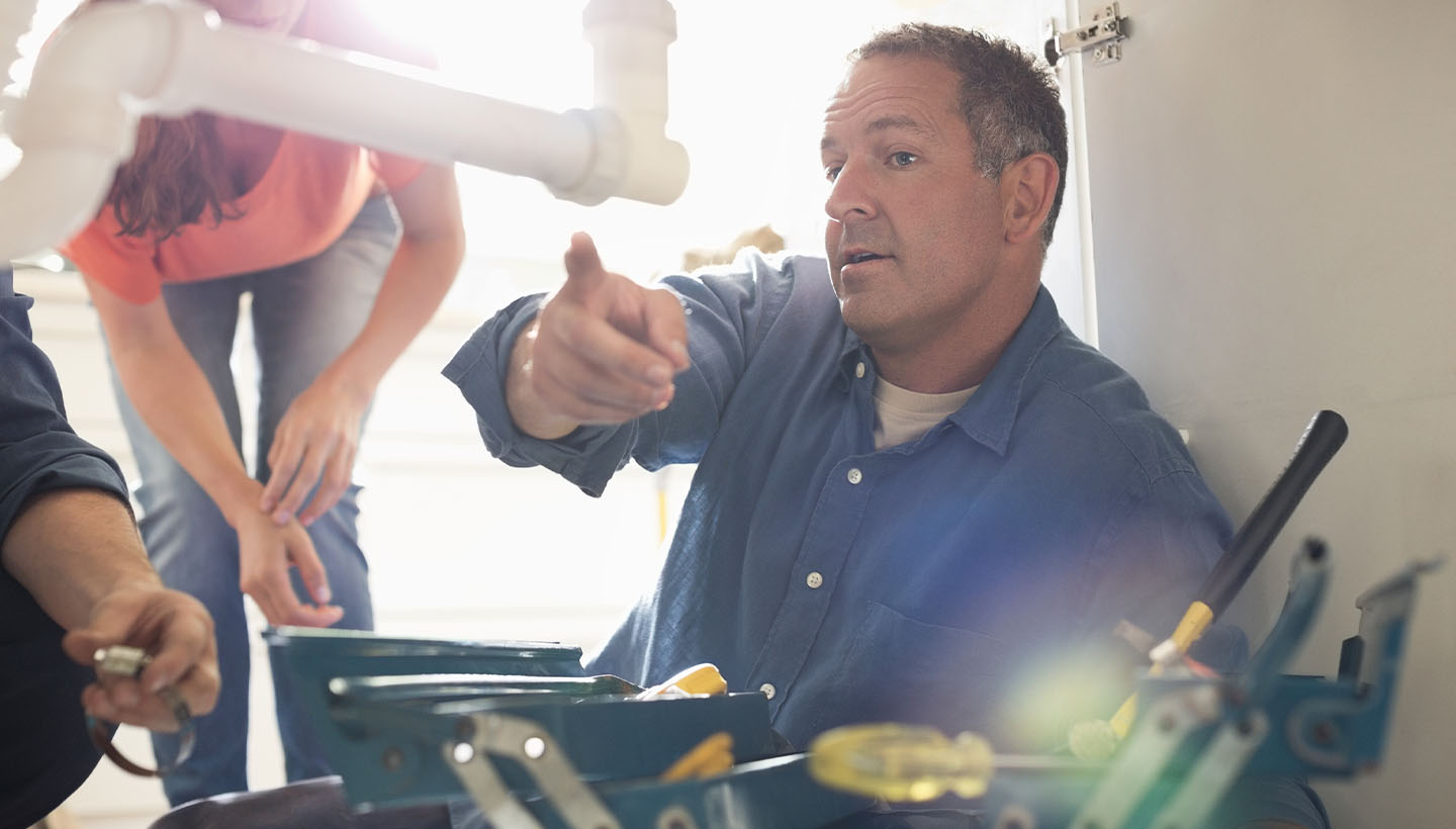 a home inspector performing a four-point home inspection and inspecting plumbing