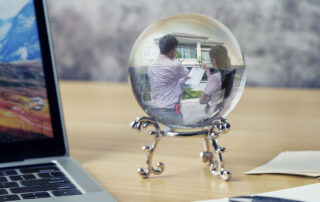 A picture of a crystal ball on a desk, depicting the home inspection industry forecast for 2026 - showing someone looking at a house from the outside, preparing to purchase it